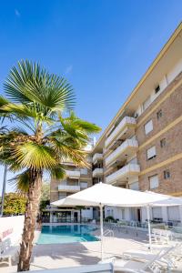a palm tree in front of a building with a swimming pool at Benelux in Lido di Jesolo