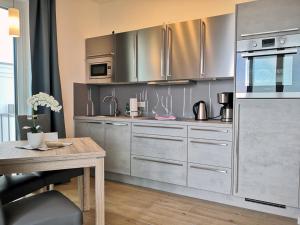 a kitchen with stainless steel appliances and a wooden table at Baabe Villen Ensemble VE 19 Meerbl in Baabe