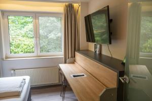 a hotel room with a desk and a tv at Hotel Haus Hohenstein in Witten