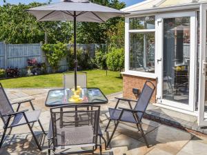 a patio with a table and chairs and an umbrella at Peace Haven in Gorleston-on-Sea