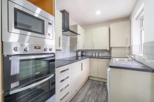 a kitchen with white cabinets and a stainless steel appliance at Stylish 3 Bed - Entire House- Near City Ctr & SUFC in Sheffield