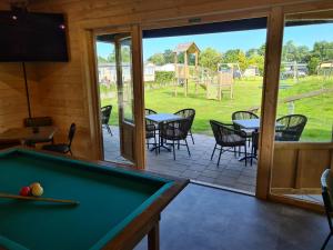 a room with a pool table and a patio at Bungalow 82 op Recreatiepark De Wielen in Sint Maarten
