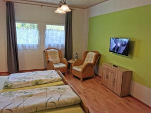 a bedroom with two beds and chairs and a tv at Landhotel Sonnenhof im Wendland in Clenze