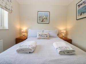 - une chambre avec un lit blanc et des serviettes dans l'établissement The Beach House, à Bridport