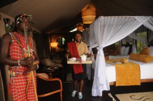 two people standing in a bedroom with a bed at Castel Mara Camp in Masai Mara