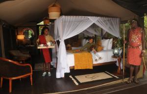 eine Gruppe von Personen, die in einem Schlafzimmer mit einem Bett stehen in der Unterkunft Castel Mara Camp in Masai Mara