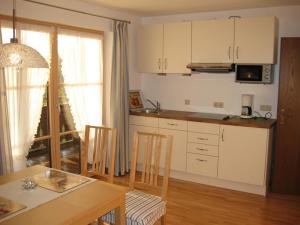 a kitchen with white cabinets and a table and chairs at Ferienwohnung Edmeier in Bernau am Chiemsee