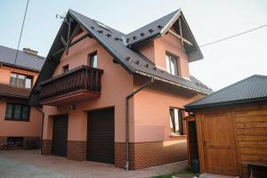 a pink house with a black roof and a garage at Spisz& Śpisz in Frydman