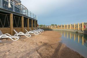 a row of white chairs on a beach next to the water at Tattershall Lakes, Castle View in Tattershall