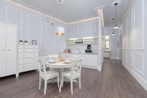 a white kitchen with a white table and chairs at Perła Starego Miasta Kamienica Czapskich by Renters in Krakow