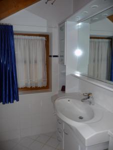 een witte badkamer met een wastafel en een spiegel bij Villa Pircher in Dobbiaco