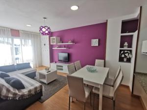 a living room with a table and a purple wall at Playa Panadeira, piso céntrico in Sanxenxo