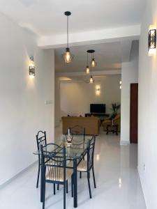 comedor con mesa de cristal y sillas en Welaratne Apartment en Nugegoda