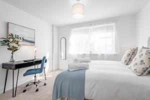 a white bedroom with a desk and a bed at Skye Sands - City Road Residence - Central St Andrews in St Andrews