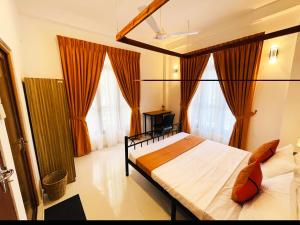 a bedroom with a large bed with orange curtains at Zeleny Apartments in Nugegoda +11 photos