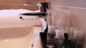 ein Waschbecken mit einem Wasserhahn und zwei Glasgläsern in der Unterkunft Blu Hotel in Buccinasco