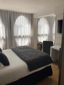 a bedroom with a bed and a desk and windows at Best Western Premier Why Hotel in Lille