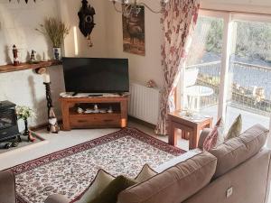 a living room with a couch and a flat screen tv at Riverside in Newton Stewart