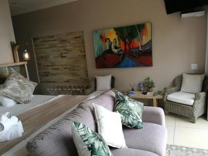 a living room with a couch and a painting on the wall at Lavandula Manor Self-Catering in Mossel Bay