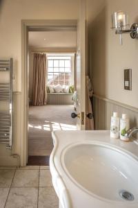 a bathroom with a white sink and a living room at The Black Lion, Long Melford in Long Melford