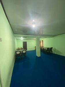 Zimmer mit blauem Boden sowie Tischen und Stühlen in der Unterkunft Hotel Border View in Kargil