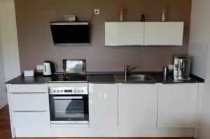 a kitchen with white cabinets and a black counter top at WEITBLICK "entspannen - wohlfühlen - aktiv erholen" in Elzach