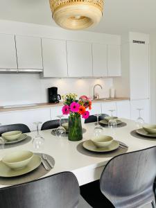 a white kitchen with a table with chairs and flowers at duinpark62: gezellig 3 slaapkamer-appartement inclusief garage in Oostduinkerke