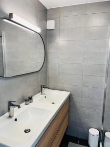 een badkamer met een wastafel en een spiegel bij duinpark62: gezellig 3 slaapkamer-appartement inclusief garage in Oostduinkerke