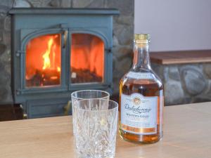 a bottle of whisky next to a glass on a table at Glebe Cottage in Urray