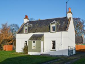 a white house with a black roof at Glebe Cottage in Urray