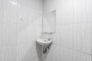 W białej łazience znajduje się umywalka i lustro. w obiekcie RedDoorz Syariah at Cigadung Raya Street w mieście Bandung