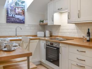 uma cozinha com armários brancos, uma mesa e um lavatório em The Stables At Early Autumn em Eynsford