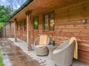 eine Veranda eines Holzhauses mit Korbstühlen in der Unterkunft The Stables At Early Autumn in Eynsford