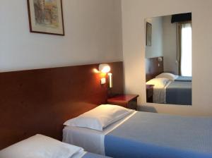 a hotel room with two beds and a mirror at Hotel San Marco in Arezzo
