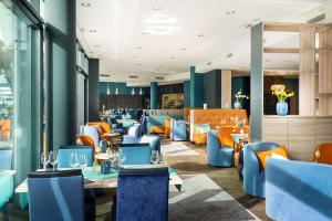 un restaurant avec des tables et des chaises bleues et oranges dans l'établissement elaya hotel kleve, à Clèves