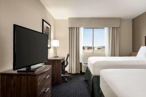 a hotel room with two beds and a flat screen tv at Baymont by Wyndham Rawlins in Rawlins