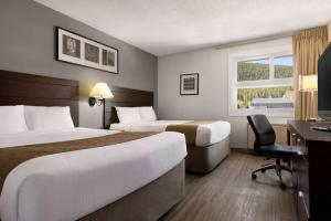 a hotel room with two beds and a desk at Travelodge by Wyndham Blairmore in Blairmore