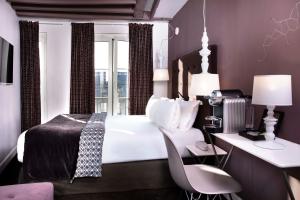 um quarto com uma cama branca, uma secretária e uma janela em Hôtel Marais Hôme em Paris