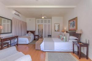a hotel room with two beds and a desk at Villa Capri Guesthouse Ballito in Ballito