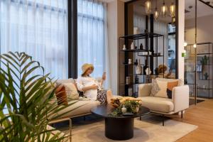 a woman sitting on a couch in a living room at Hôtel Joe M in Paris