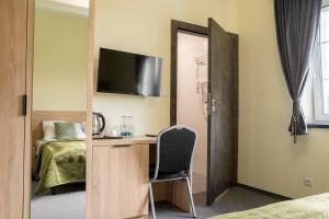 Zimmer mit einem Schreibtisch, einem TV und einem Bett in der Unterkunft Przy Skarpie Rozbark in Bytom