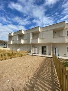 a large white building with a wooden fence at SULLA SPIAGGIA VILLETTA A SCHIERA int.11 in San Pietro in Bevagna