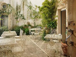 eine Außenterrasse mit Tischen, Stühlen und Pflanzen in der Unterkunft Relais Il Mignano in Nardò