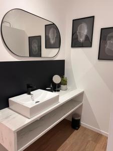 La salle de bains est pourvue d'un lavabo blanc et d'un miroir. dans l'établissement Appart'Alencon, à Aleçon