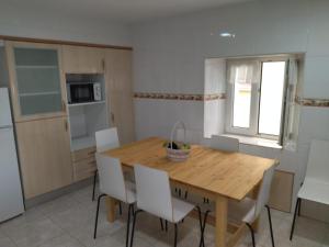 a kitchen with a wooden table and white chairs at Fuentinueva in Ampuero