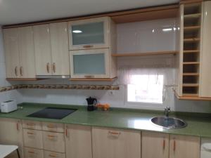 a kitchen with white cabinets and a sink and a window at Fuentinueva in Ampuero