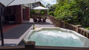 a hot tub on a deck with an umbrella at Marula Mews T17 Villa - Selborne Golf Estate in Kelso