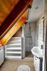 a bathroom with a door leading to a shower and a sink at Bazaltorgona 37 in Badacsonytördemic