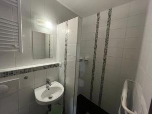 a white bathroom with a sink and a shower at Centrál Borház - Étterem és Panzió in Érd