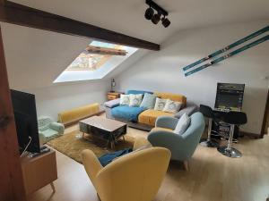 ein Wohnzimmer mit einem Sofa und einem TV in der Unterkunft Le Trésor des Vosges Appartement spacieux et lumineux 80m2 idéal famille 4 à 6 personnes in Gérardmer